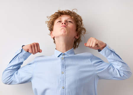 strong teen boy show biceps at camera, caucasian boy has power. isolated white backgroundの写真素材