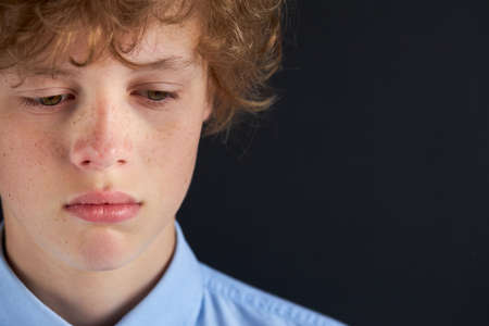 close-up portrait of sad caucasian boy looking down, depressed boy has bad mood, in contemplationの写真素材