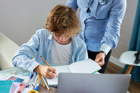 math teacher teach young teen boy at home, explain math tasks and equations, do homeworkの写真素材