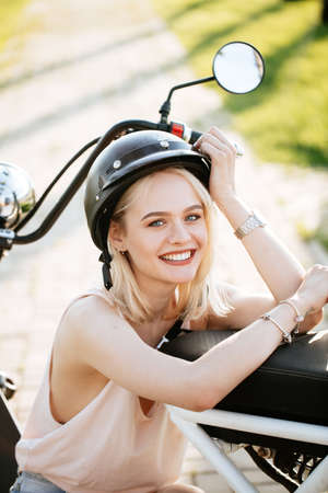 Beautiful female biker of european appearance with biking helmet on head relaxing after riding on electric bike, Close-up portrait of female cyclist at summer time vacation or holiday .の写真素材