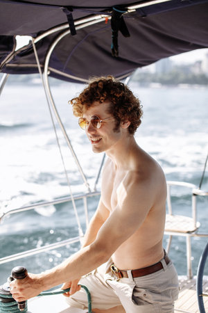 Cropped view of yacht captain working on the boat with winch on a sailboat during the ocean voyage,...