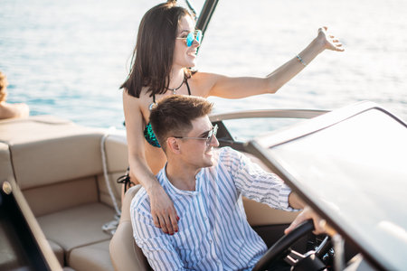 Newly married caucasian couple driving sailboat, enjoying water summer adventure, spending honeymoon...