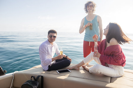 People on yacht drinking beers while talking - Group of friends having party on sailing boat