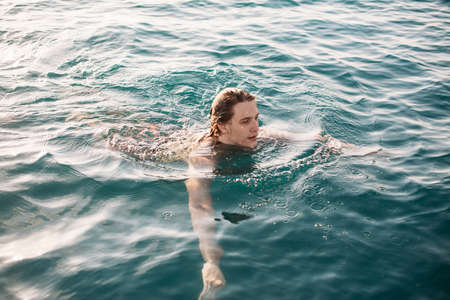 Young man swimming at sea water, enjoying open water space and warm calm water.の写真素材