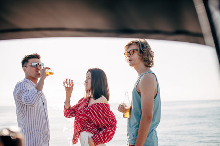 People on yacht drinking beers while talking - Group of friends having party on sailing boat