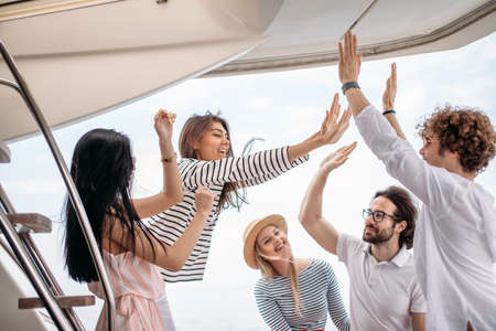 All together we done it! Conception of successful teambuilding. Five happy students putting their hands up together, celebrating their successful examsの写真素材