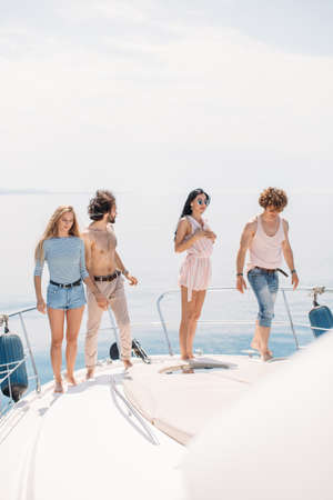 playful , caucasian heterosexual friends dancing on a bow of yacht , hot dancing against blue sea background with copyspace . Beautifyl youngsters.の写真素材