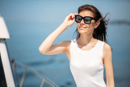 Young, attractive and rich caucasian businesswoman engages a yacht, having fotossesion on a luxury boat in sea at sunny summer dayの写真素材