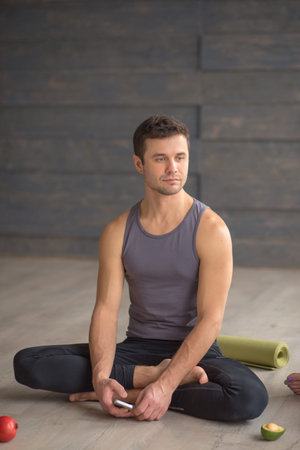 Athletic caucasian man in sport wear relaxing after yoga class over grey studio background, sitting in lotus posture.の写真素材