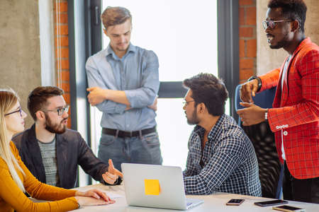 Chief Executive and his male assistants thinking over the results of accountant financial report of the last start-up projectの写真素材