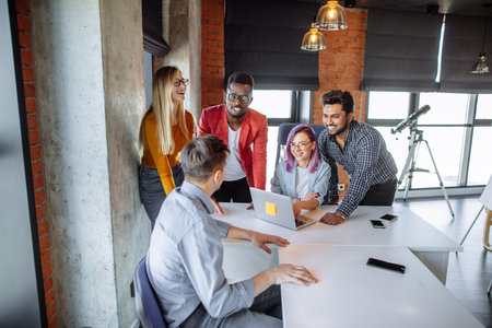 Indoor shot of group of multiracial students having meeting at loft studio space background, using...