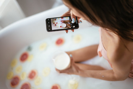 Unrecognizable traveller blogger woman testing a new service in hotel, relaxing batroom with milk...