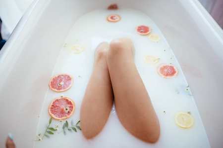 High angle view of woman legs lying and relaxing in bathtube with milk, body detail, sexy erotic...