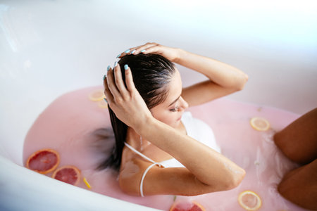 Gorgeous brow-haired woman posing in the bath with pink coloured milk - beauty glamour portrait....