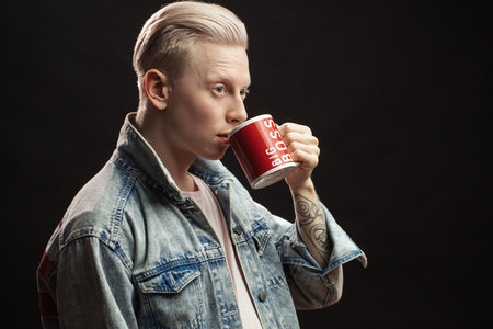 Casual young blonde handsome male model wearing jean jacket posing at studio. Mens beauty, fashion....