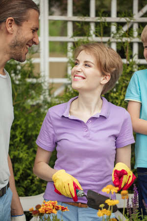 Happy parents, planting flowers in pots, preparing garden to birthday celebration, outdoors. Active leisure with kids. Family, Relations, Parenthood, Gardeningの写真素材