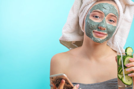 isolated studio portrait of woman getting spa treatment , with clay nourishing mask, covering her...