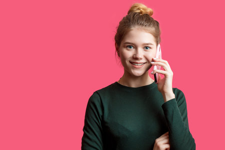Portrait of young beautiful cute cheerful woman smiling looking at camera while holding smartphone...
