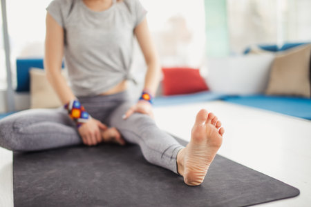 Cropped view of woman making asana exercises doing Head to Knee Forward Bend pose. Healthy lifestyle in fitness club.の写真素材