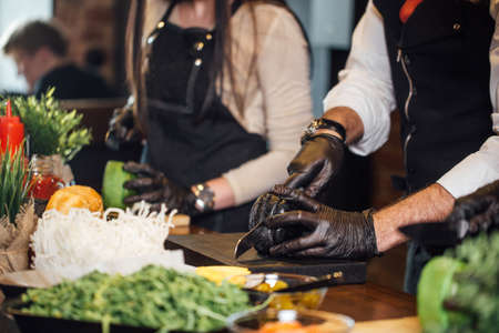 Cropped view of Chefs hands standing in raw at table and making hamburgers and burgers.の写真素材
