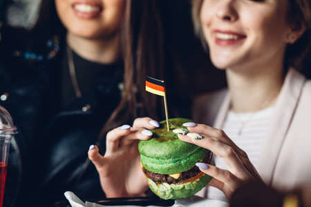 Cropped view of smiling woman enjoying a delicious and tasty green burger in the burger-barの写真素材