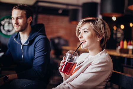 Group of young people sitting at music hall, listening music, talking and enjoying cold berry lemonadeの写真素材
