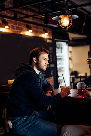 Portrait of pencive young businessman sitting at the counter with beverage in a cafe with loft...