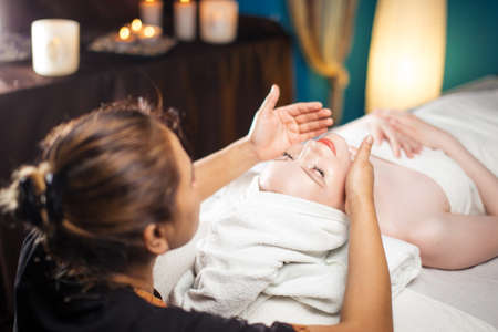 Healthful Leisure Time. Satisfied pleasant female client having face massage in spa complex.の写真素材