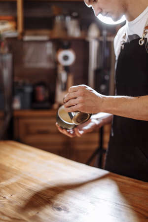 coffee artist . creative barista with coffee cup and pot. close up side view cropped photoの写真素材
