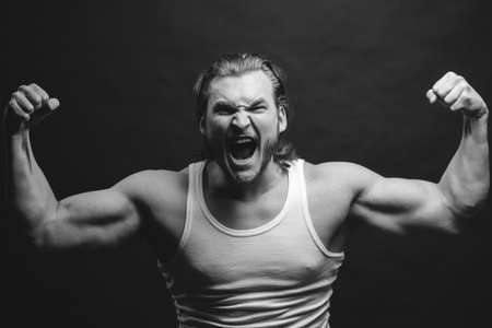 black and white photo. angry sportsman showing his hard musculars. force concept. physical powerの写真素材