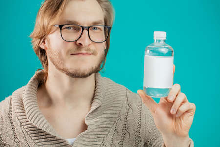 young handsome muscular man with fair hair holding a bottle of water. thirst concept. mineral water. refreshnet. drinkの写真素材