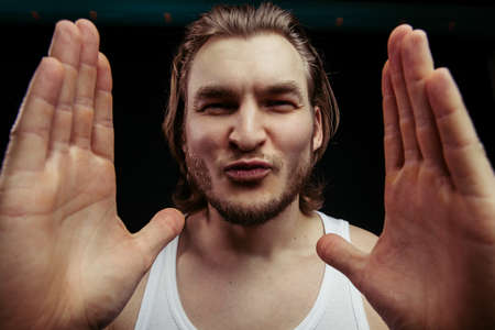 funny strong man in white singlet is going to kiss photographer, camera.sentimental sportsman, bodybuilderの写真素材