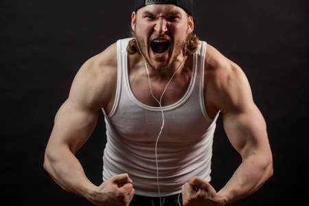 angry man with open mouth is tensing his musclesの写真素材