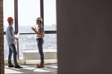 team of hardworking architects wearing hardhat are standing on construction background. black copy space.の写真素材
