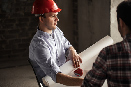 pensive engineer in red hat is counting the flies. close up side view photo. thinking processの写真素材
