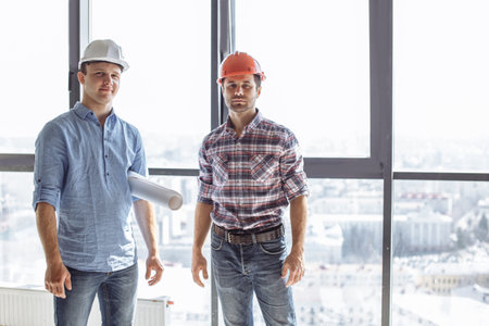 creative engineears are looking at the camera at workplace. panorama window on the background of the...