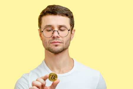 a young nice man looking at the coin.expertize the coin. handsome student has found a golden coin