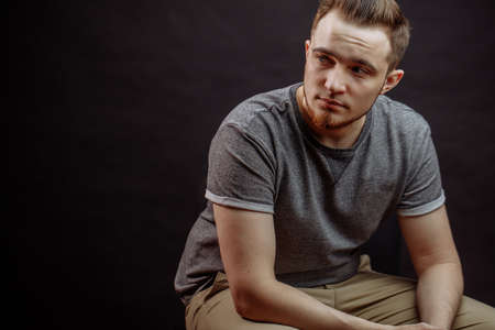 close up portrait of pensive young fashion man sitting on the chair. copy spaceの写真素材