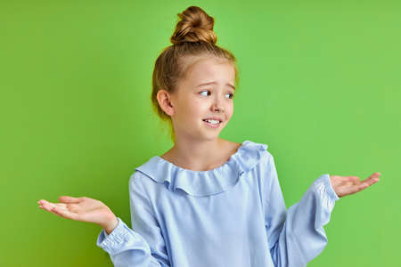 attractive caucasian girl doesnt know, shrugging and looking away, misunderstanding. isolated green backgroundの写真素材