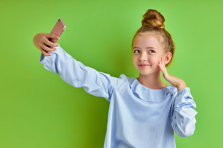 emotional crazy little girl take photo on phone, alone. beautiful kid girl make selfie, posingの写真素材