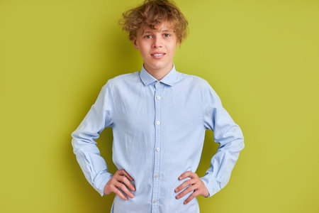 unperturbed caucasian boy isolated over green background, kid boy 14-15 years old in blue shirt look...
