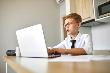 little boy hold online conference via webcam, sit looking at screen of laptop and talk, in formal...