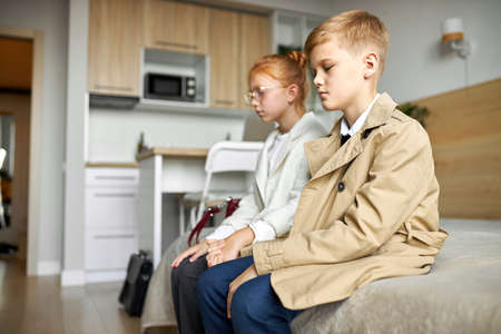 offended on each other girl and boy sit on bed in coats, they have no talk, keep silence, indoorsの写真素材