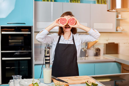 funny female chef with grapefruit on her eyes. good, positive mood while cooking