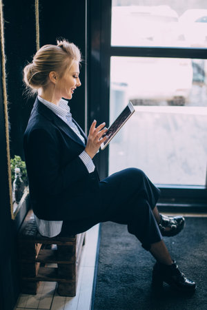 beautiful journalist dressed in formal clothes is working with tablet. close up side view photo.