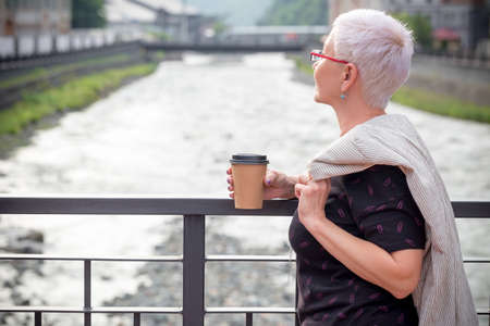 back view photo. woman is enjoying the beauty of nature and river while standing on the bridge. blurred backgroundの写真素材