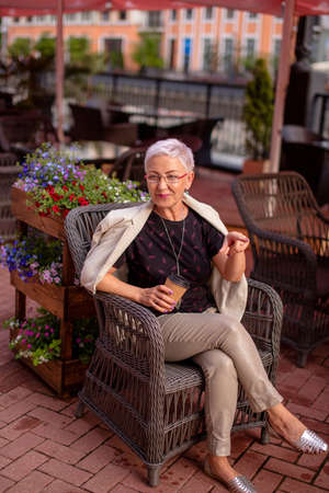 pleasant woman is sitting at the cafe and pointing at somewhere. point the wayの写真素材