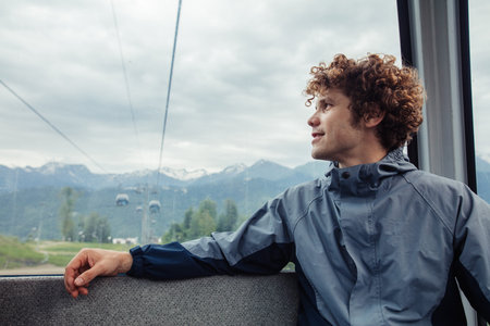 young handsome man is resting in the funicular. awesome ginger tourist going sightseeng with...