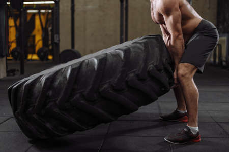 close up cropped side view photo of sportsmans body with wheel in the sport club. focus on the tireの写真素材
