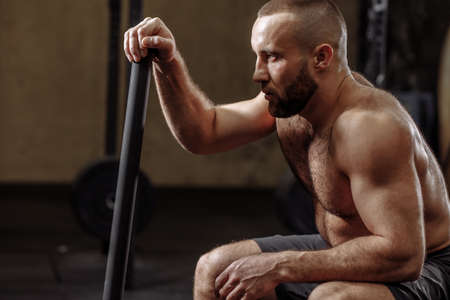 close up sside view photo. bearded fit man leaning on the hammer while having a restの写真素材